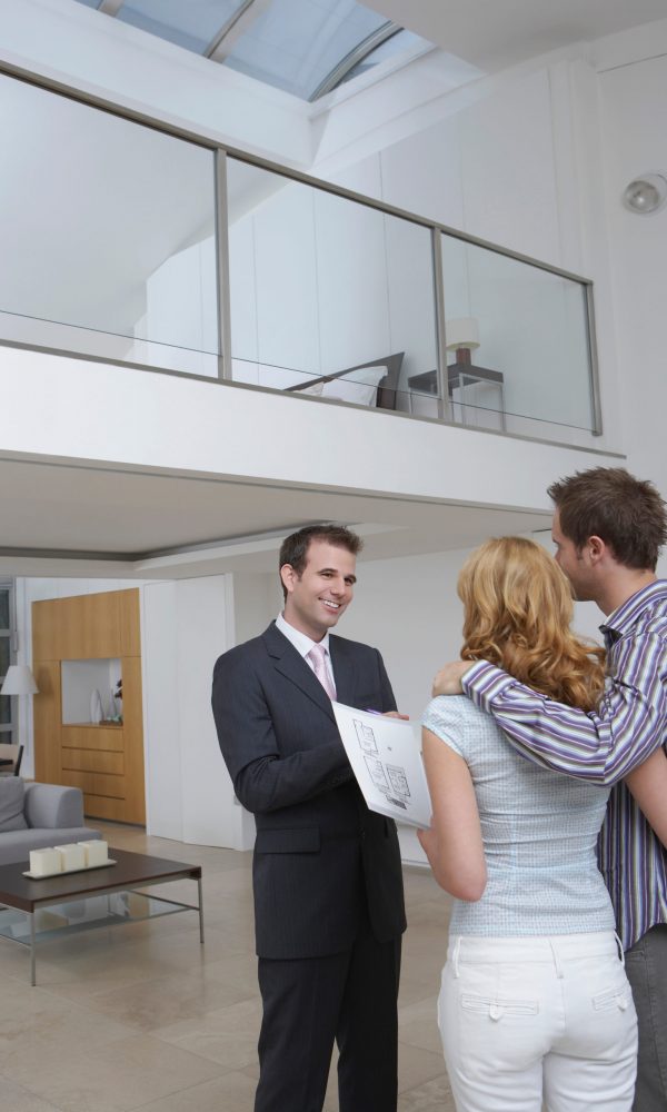 Friendly male real estate agent showing couple new home